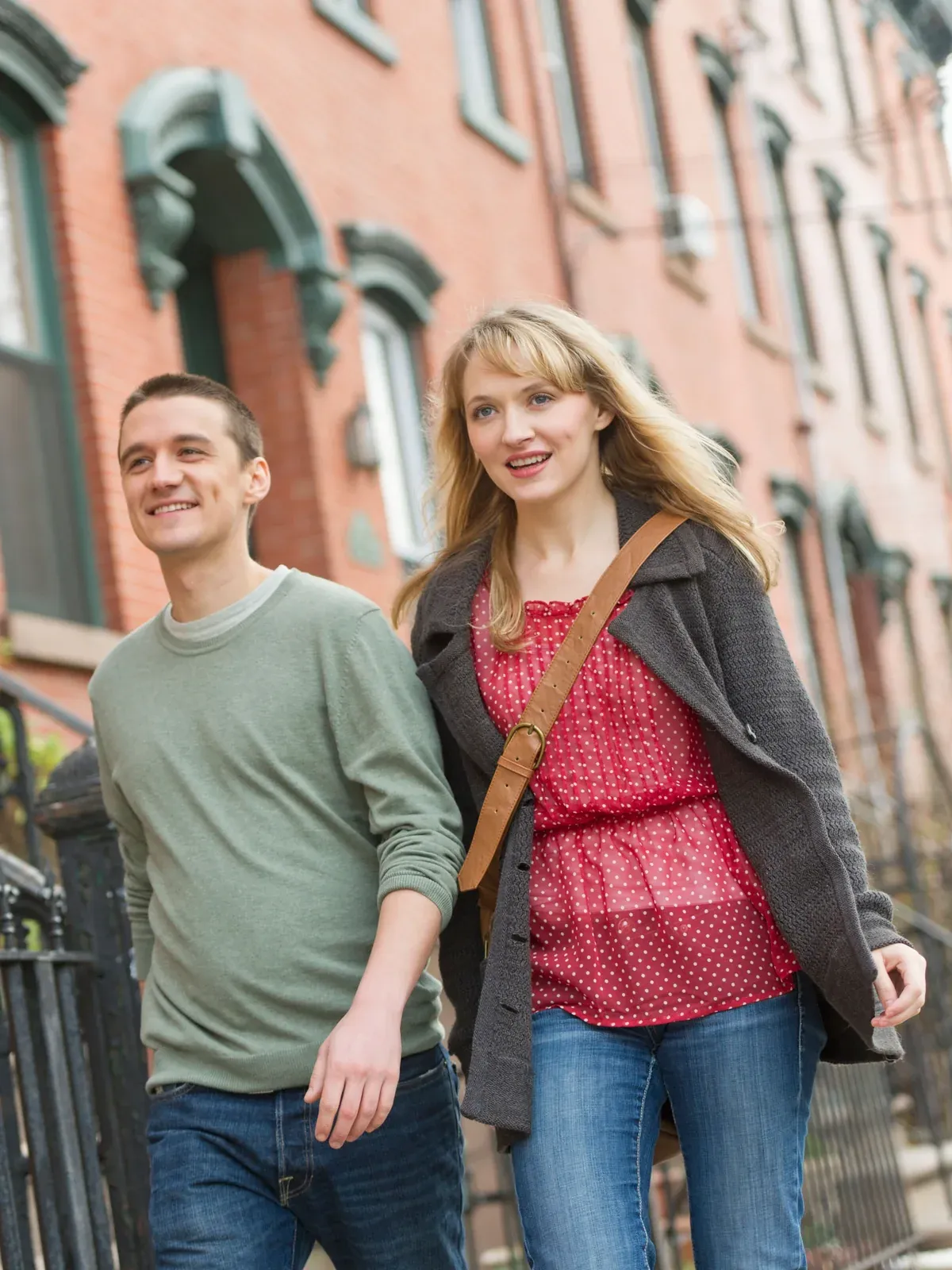 A couple walks past brick rowhouses in Jersey City.