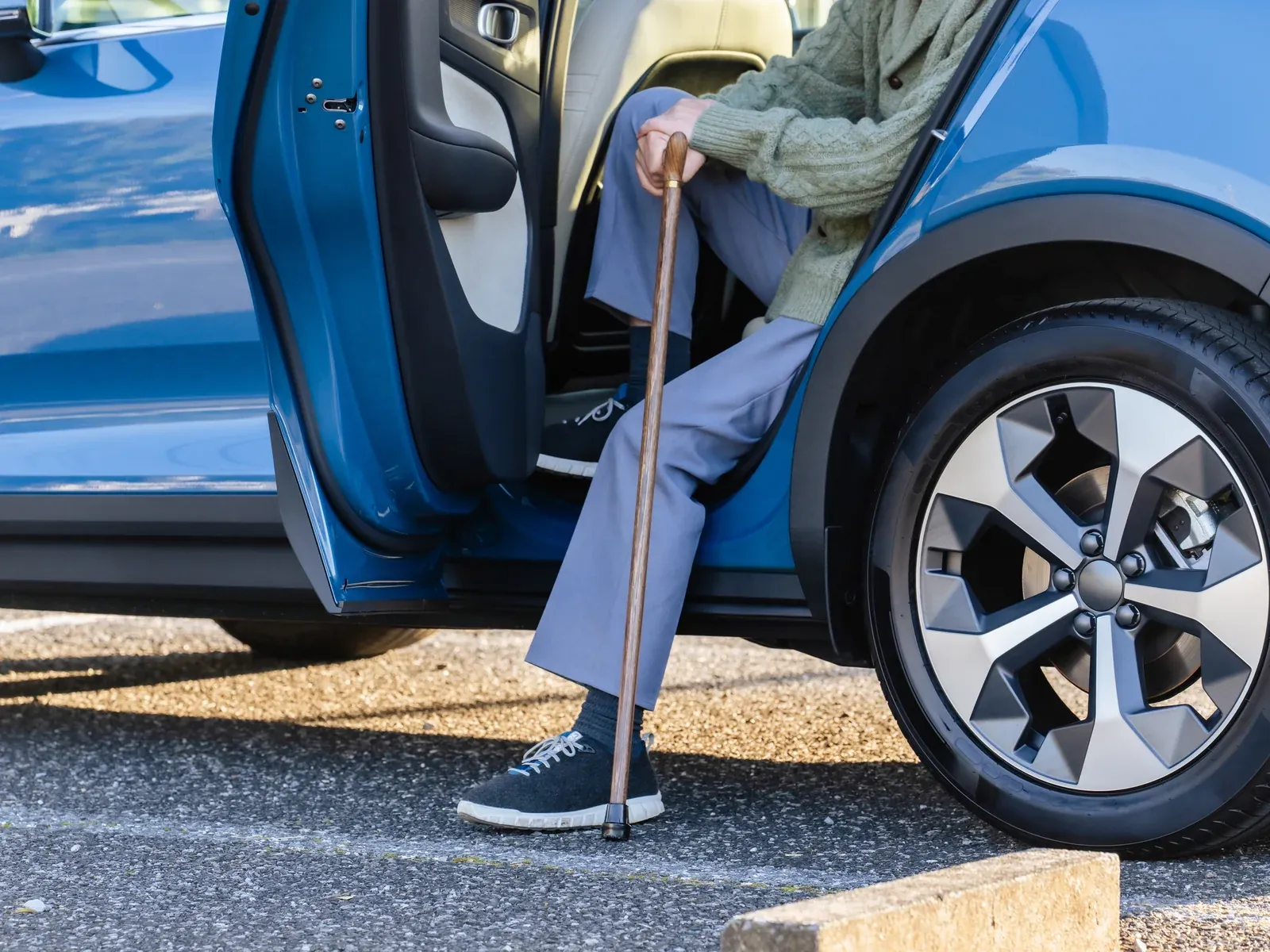 A person with a cane steps out of a car.